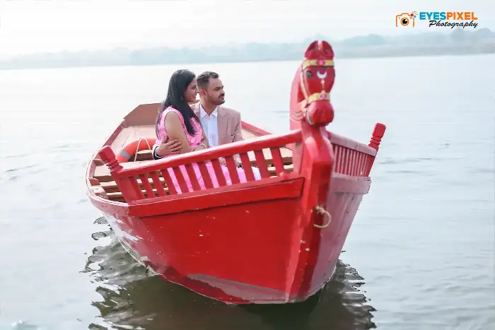 Couple seated together in a red wooden boat on open water
